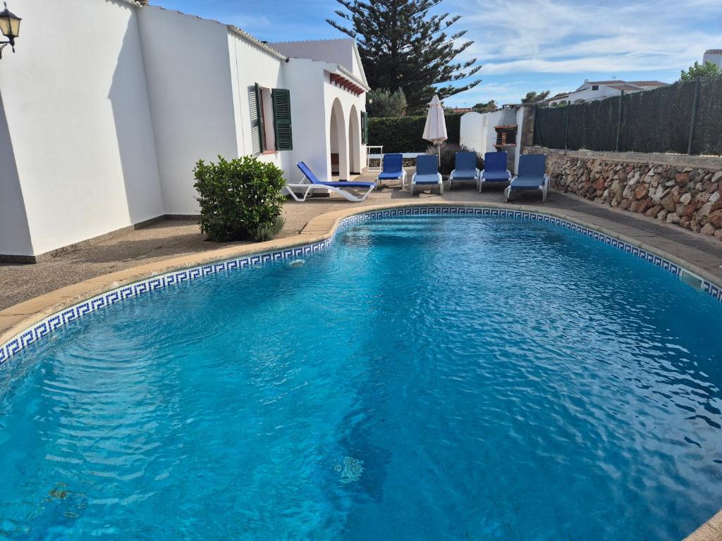 a swimming pool with chairs and a house at Villa familiar con piscina privada en Calan Blanes in Cala en Blanes