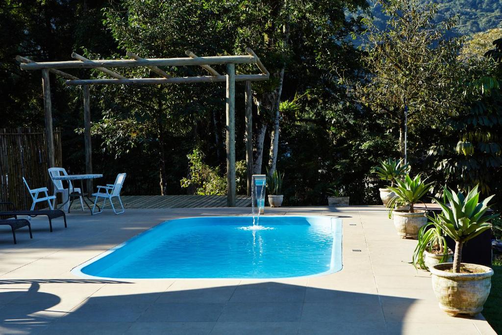 a swimming pool with a water fountain in a yard at Pousada Rancho da Serra PETAR in Iporanga
