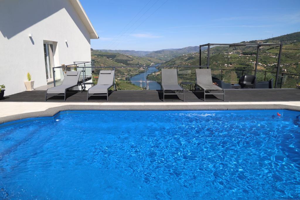 a pool with chairs and a view of a house at Casa Vale do Douro in Mesão Frio