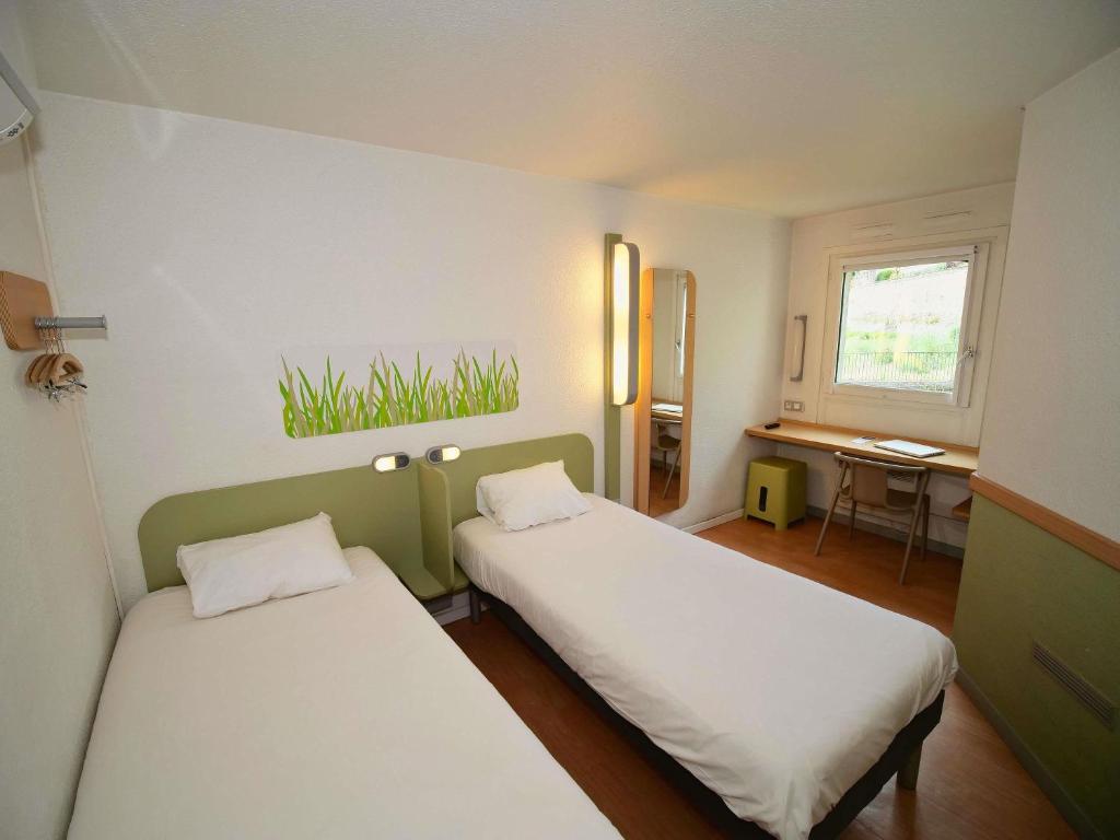 a room with two beds and a desk and a window at ibis budget Blois Centre in Blois