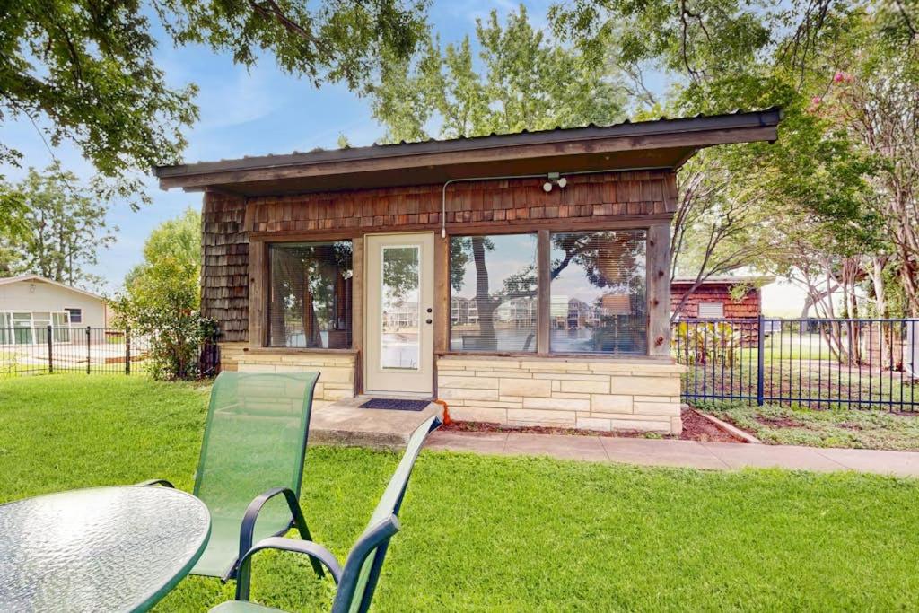 a small building with a table and chairs in the grass at Classic Lakefront Cottage with Private Dock, Lovely Lake View, Backyard & WiFi in Kingsland