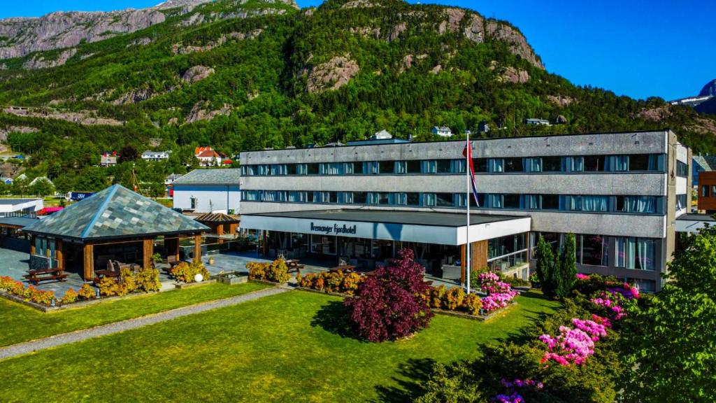 a building with a garden in front of a mountain at Bremanger Fjord Hotell in Svelgen