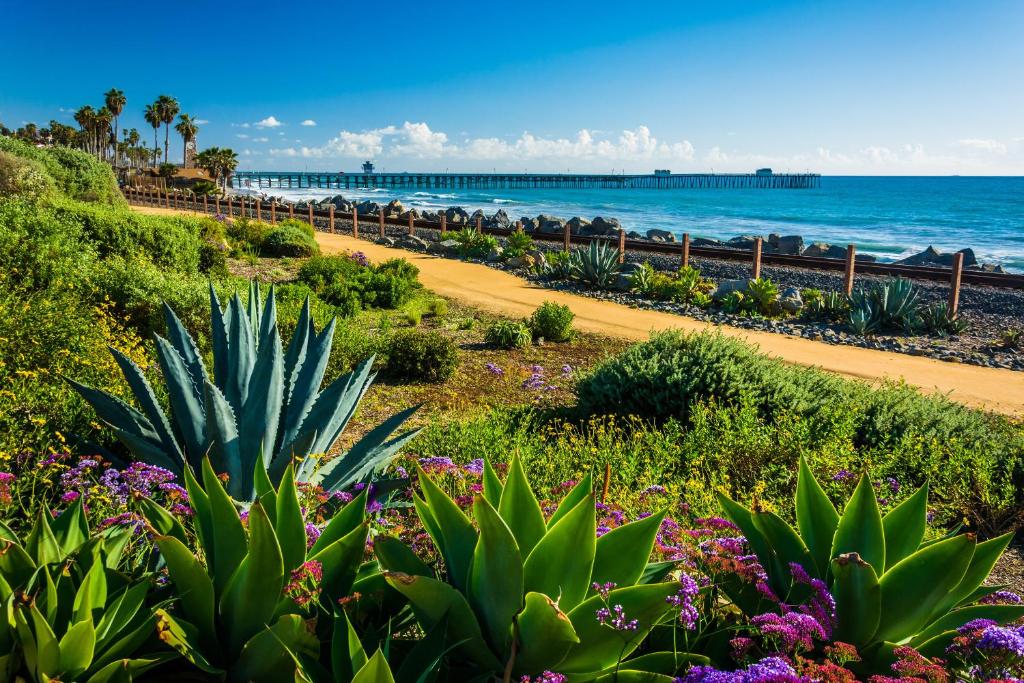 a garden with flowers and the ocean in the background at San Clemente Surf Inn in San Clemente