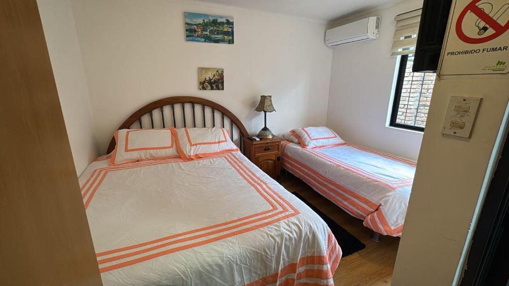 a small bedroom with two beds and a window at Hostal Almendral in San Felipe