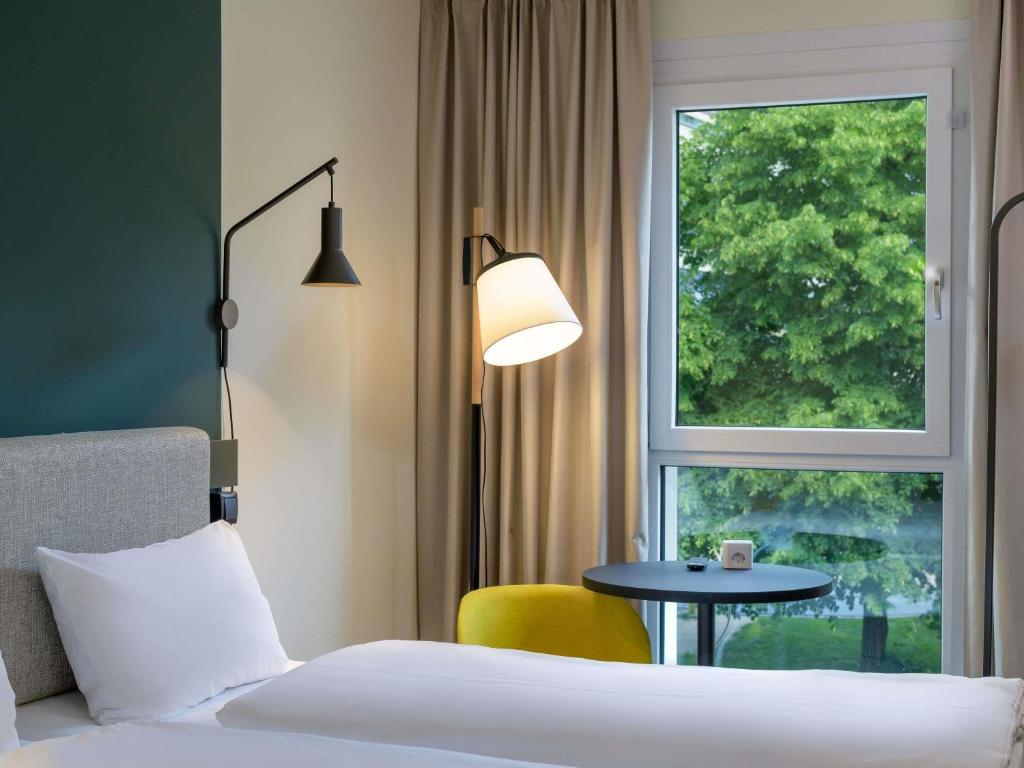 a hotel room with a bed and a table and a window at ibis Leipzig City in Leipzig