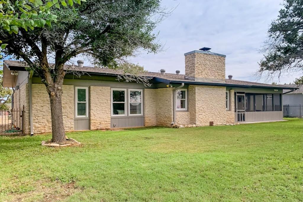 a brick house with a tree in the yard at Peaceful Mid-Century Escape with Screened Porch & Lake Access in Lago Vista