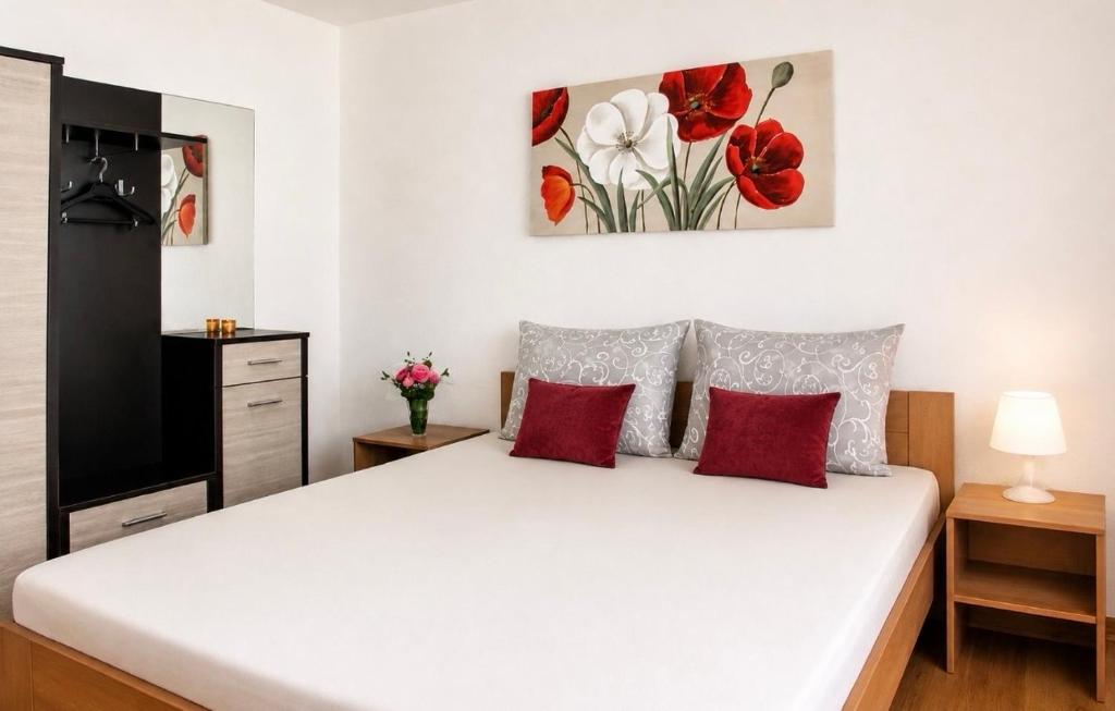 a bedroom with a large white bed with red pillows at Becar Pyramids B&B in Visoko