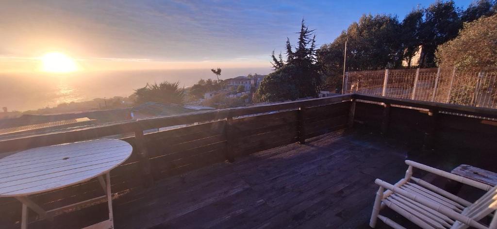 a table and a chair on a balcony with the sunset at Cabañas Caprumadp in Quintero