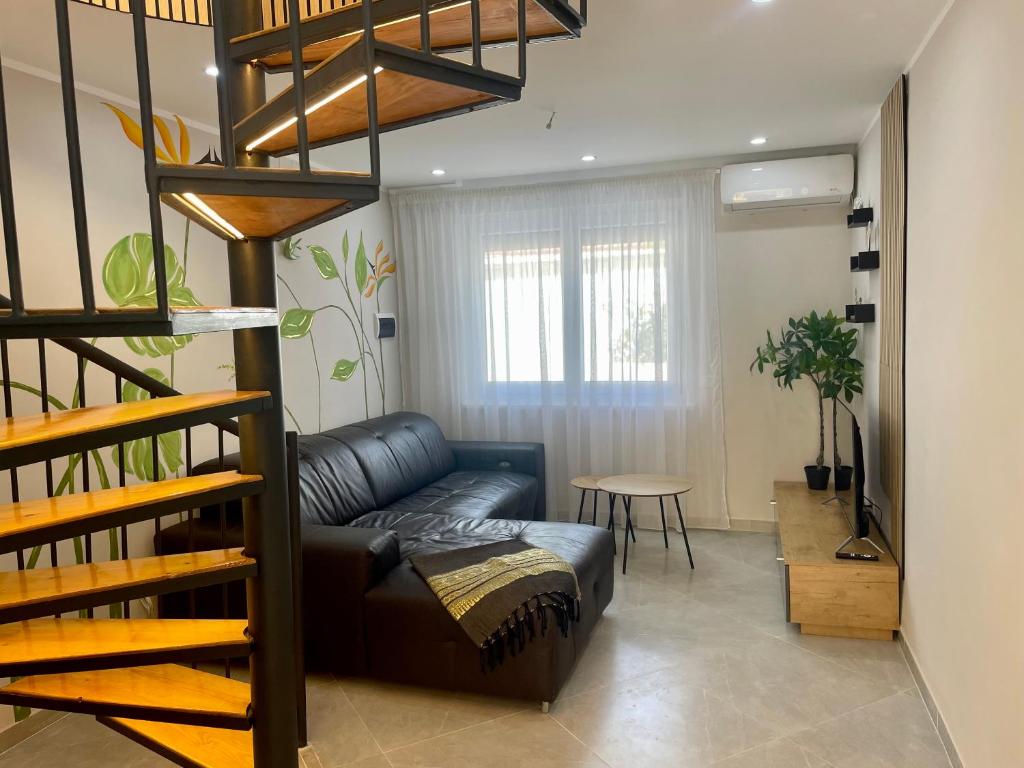 a living room with a black leather couch and stairs at La Perle de Bizerte in Banzart