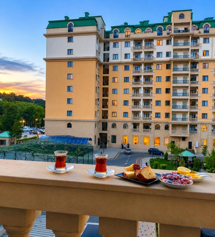 a table with two plates of food on a balcony with a large building at Caspian Residence in Sumqayıt