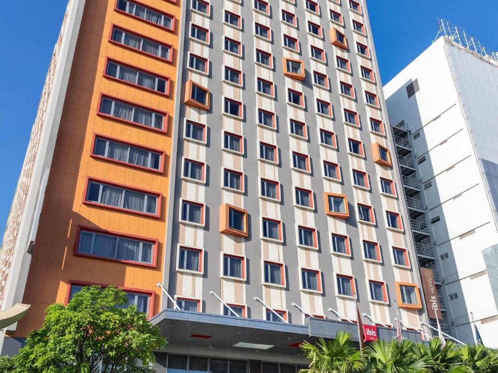 an orange and white building with trees in front of it at Ibis Saigon Airport in Ho Chi Minh City