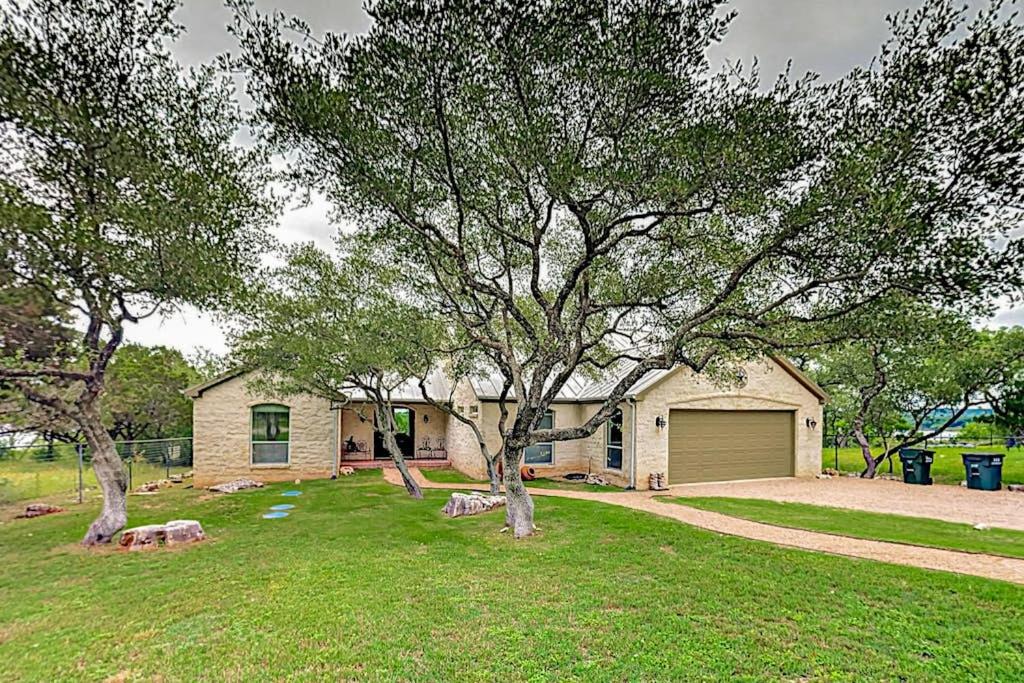a house with a large tree in the yard at Natural Cliffside Oasis with Impressive Views, Gas Fireplace and Dock in Spicewood