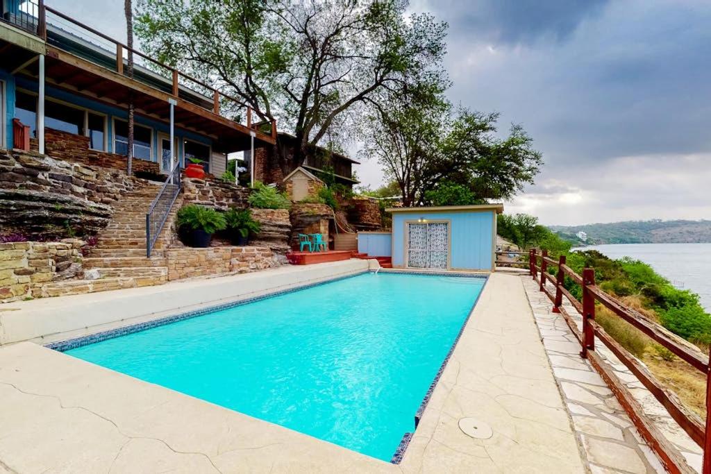 a swimming pool in front of a house at Mid-Century Modern Lake House with Private Waterfront Pool & Boat Dock in Marble Falls