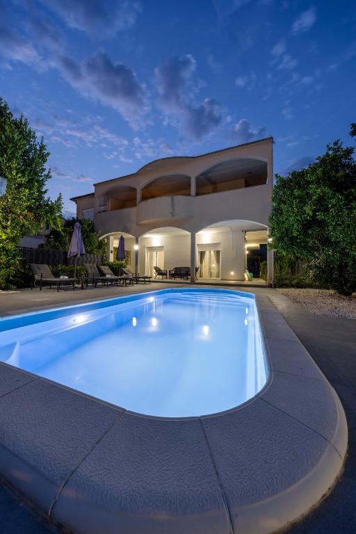 a swimming pool in front of a house at Ilma Apartment in Trogir