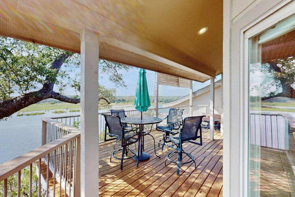 a porch with a table and chairs and a umbrella at Refined Panoramic Paradise on Lake Travis with Boat Launch and Tesla Charger in Spicewood