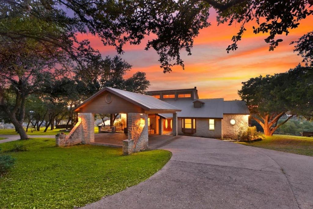a home with a sunset in the background at Regal Riverfront Home with 2 Cabins - 2 Miles to Marina in Spicewood