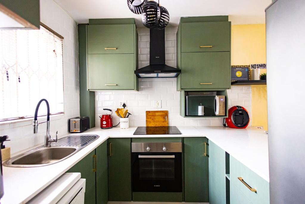 a kitchen with green cabinets and a sink at KADESE Holiday North Beach Durban in Durban