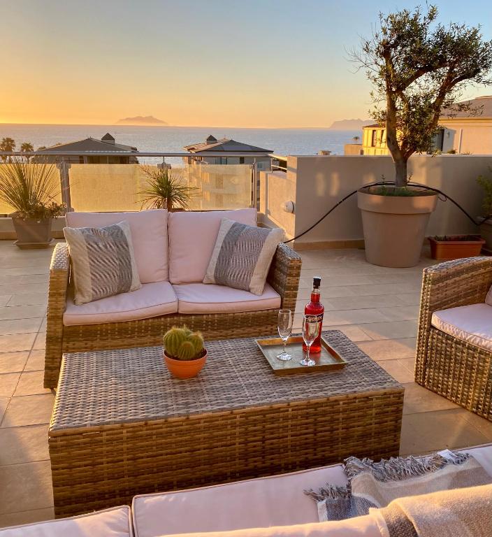 a patio with a couch and a table with a drink at Penthouse Le Isole - Luxury rooftop retreat in Marsala