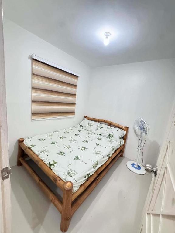a small bedroom with a bed and a fan at Home Vacation in Ormoc City in Catmon