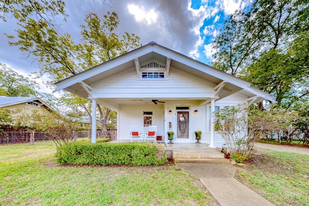 a white house with a front porch with red chairs at Enchanting Home with Fireplace, Full Kitchen, Patio, Central AC, & Washer/Dryer in Fredericksburg