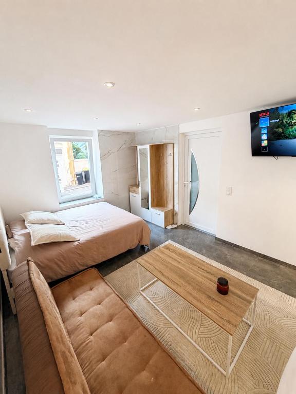a bedroom with a bed and a table and a tv at Le Cosy de Longwy in Longwy