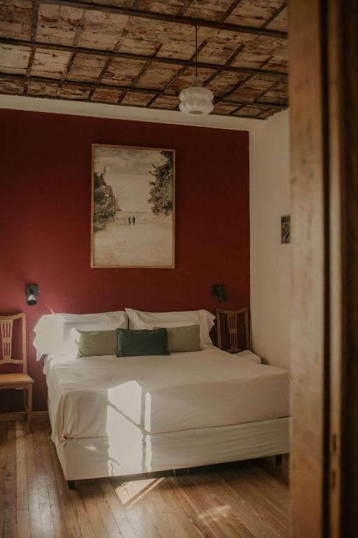 a bedroom with a white bed with a painting on the wall at La Noire Petit hotel in Buenos Aires