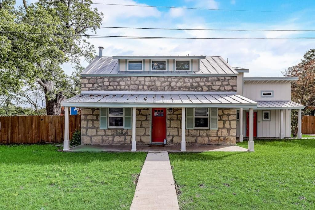 a stone house with a red door in a yard at Downtown 2-Story Home with Enclosed Backyard, Patio, Pool, Playground, W/D, AC in Fredericksburg