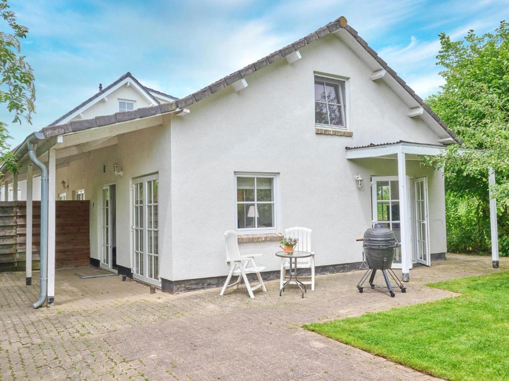 a white house with two chairs and a grill at Spijk vakantiehuis in Spijk