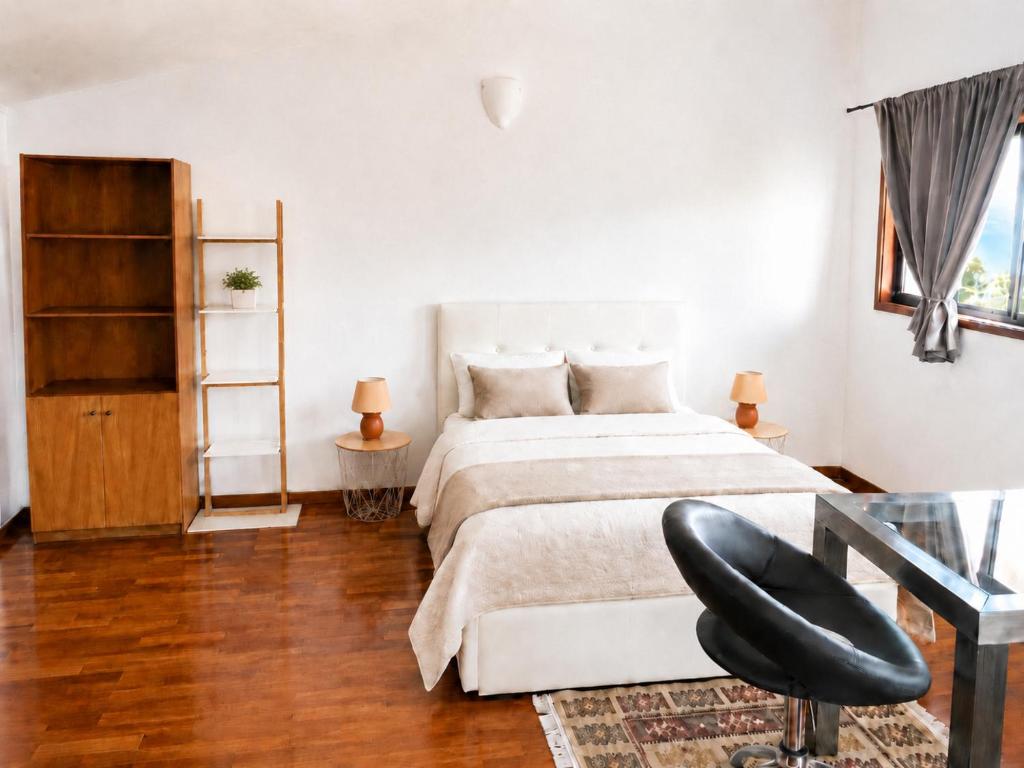 a bedroom with a white bed and a black chair at Sweets Suites Espinho in Espinho