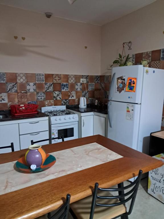 a kitchen with a table and a white refrigerator at Departamento de los pájaros in Córdoba
