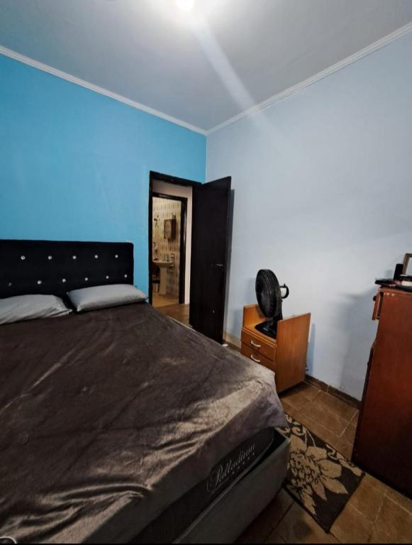 a bedroom with a bed and a blue wall at Pousada Praia Grande in Mongaguá