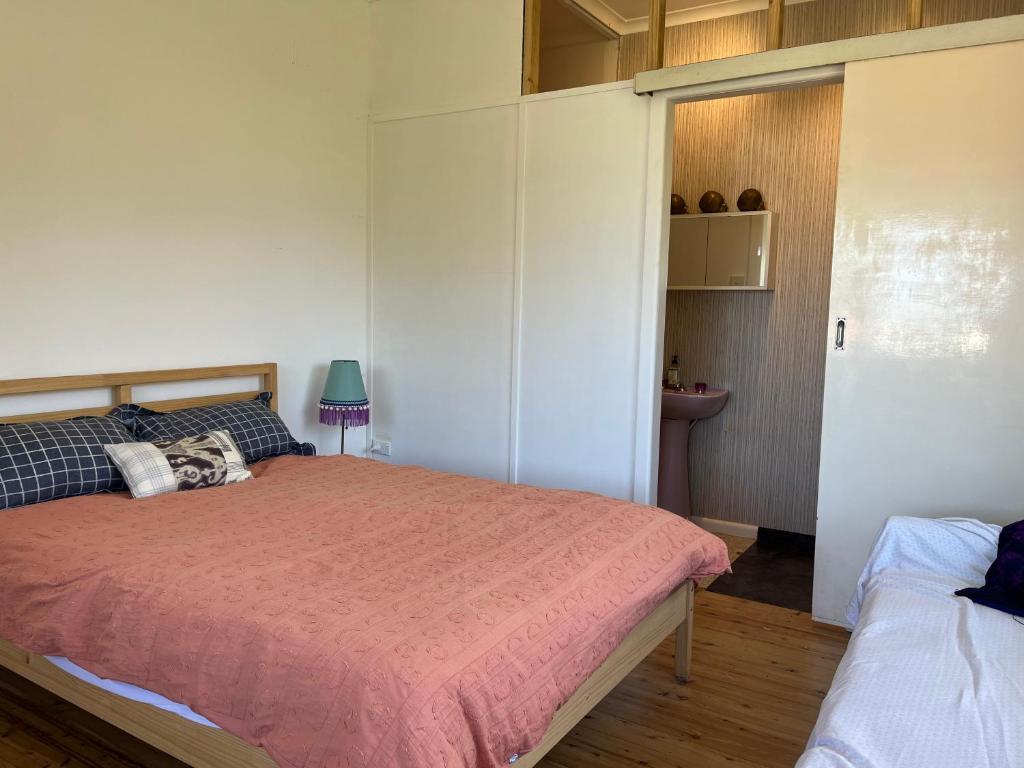 a bedroom with a bed with a pink blanket at 1 Bedroom Flat with Private Kitchen & Ensuite in Bulli