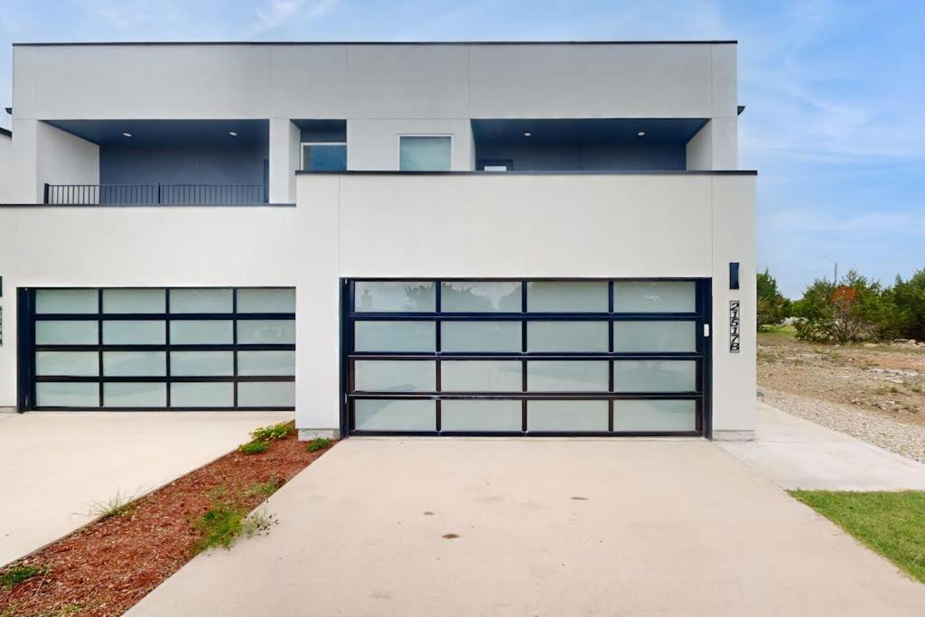 a white house with two garage doors at Modern Lago Vista Home with Balcony, Patio, Gas Grill, WIFI, and AC in Lago Vista