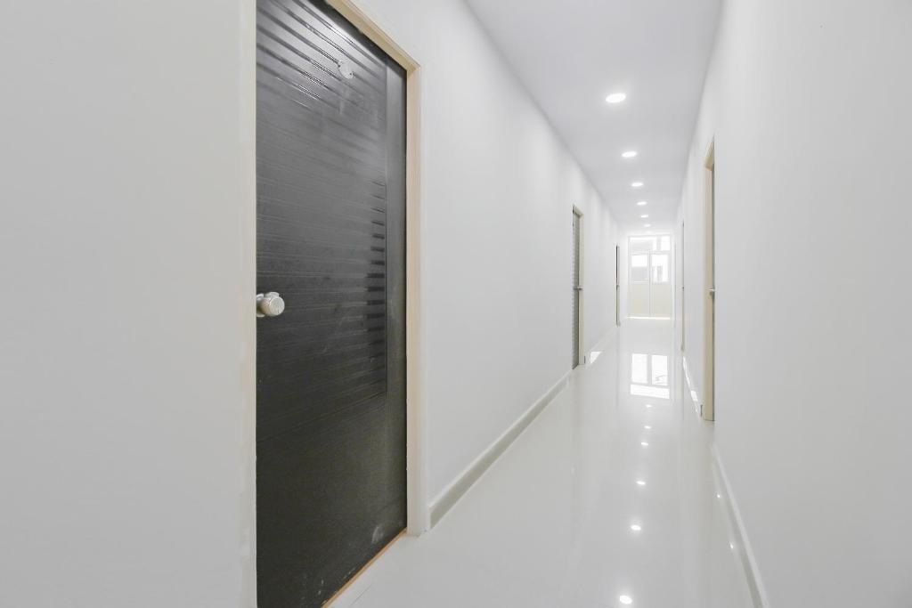a hallway with a black door and white walls at SPOT ON Pnd Complex in Hyderabad