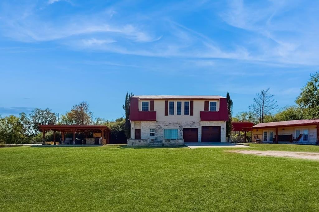 a house with a green lawn in front of it at 4-Bedroom Spacious Home with Guest House & Pool, Located on 9 Acres of Land in Spicewood