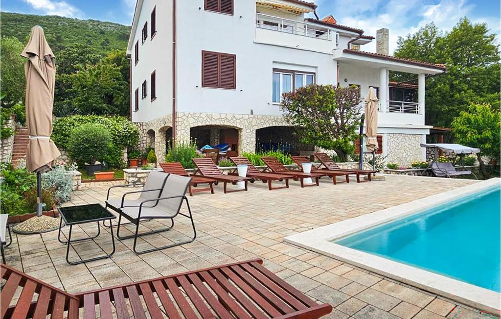 a patio with chairs and a swimming pool and a house at Apartment Ravni V in Labin