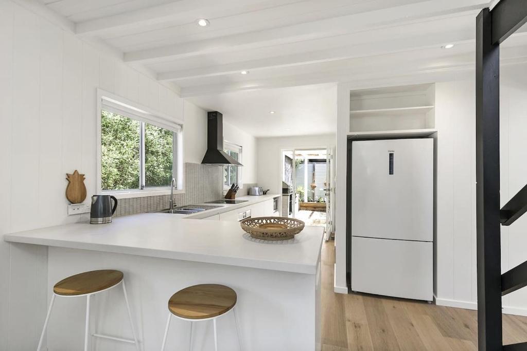 a white kitchen with a white refrigerator and stools at Beach at Your Doorstep - Pet Friendly in Anglesea