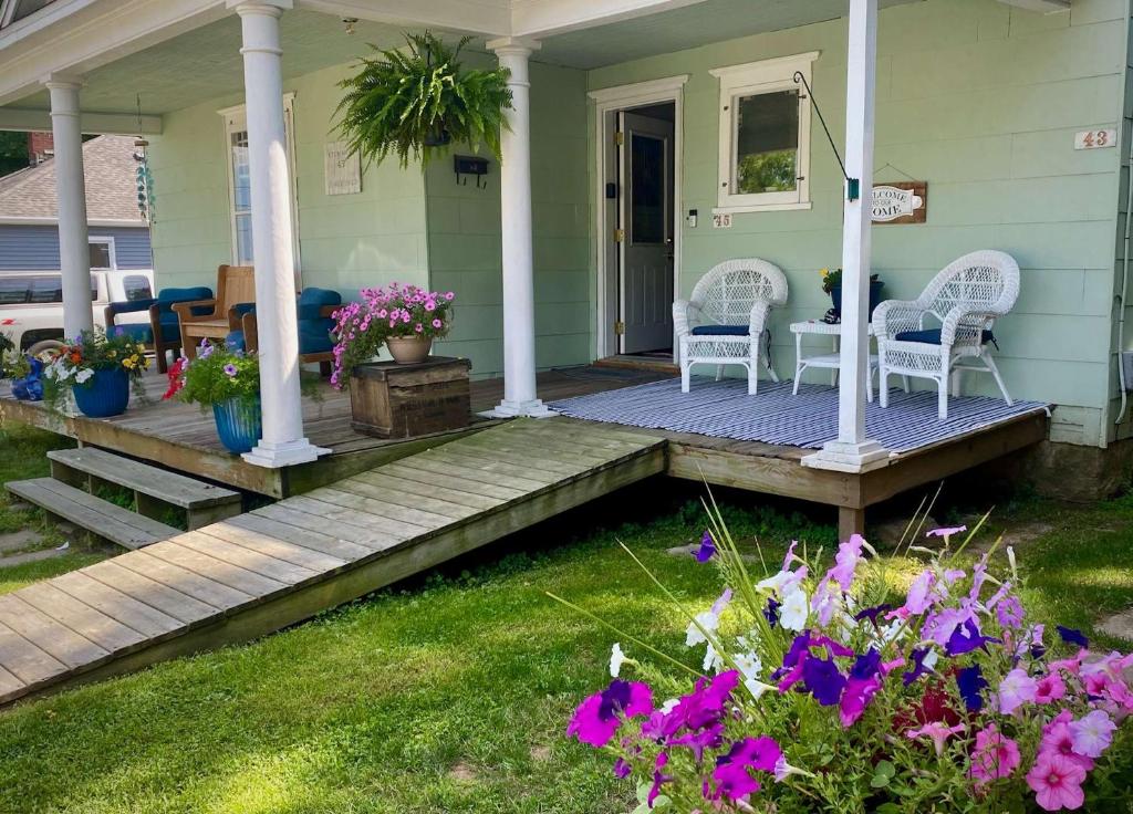 a porch of a house with two chairs and flowers at Stowaway Lower Deck in Sturgeon Bay