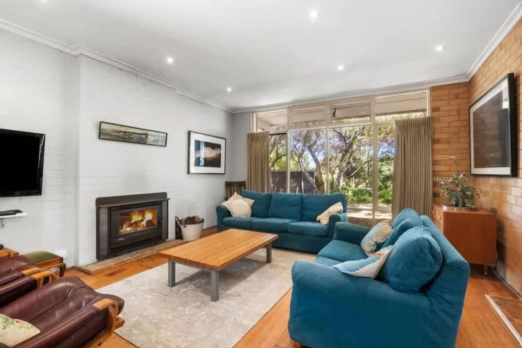 a living room with blue couches and a fireplace at Saltwinds - Steps to Beach & Lighthouse in Aireys Inlet