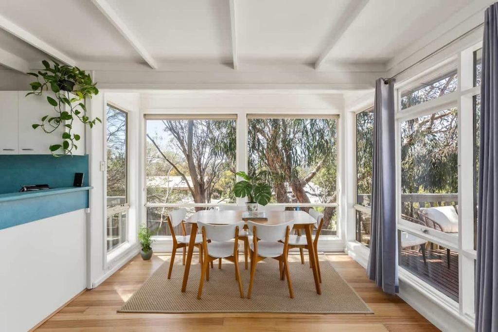 a dining room with a table and chairs and windows at Sunny Coastal Retreat in Anglesea