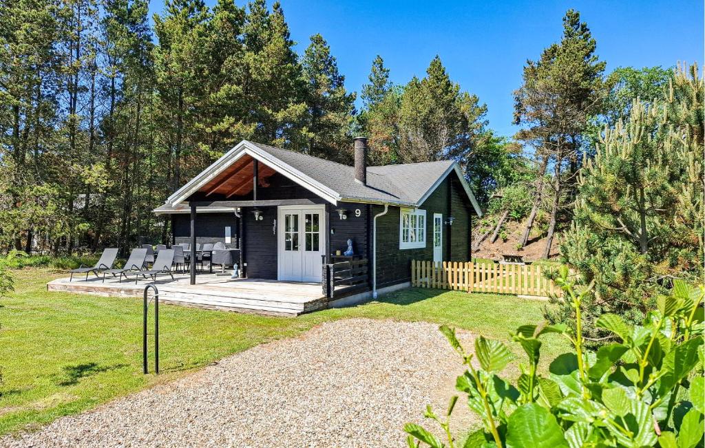a green cottage with a porch and chairs in a yard at Awesome Home In Hurup Thy With Wifi in Sønder Ydby