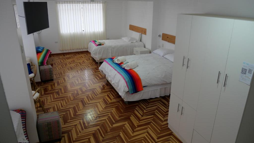 a bedroom with two beds and a tv in it at Casa jardín Roqui in Puno