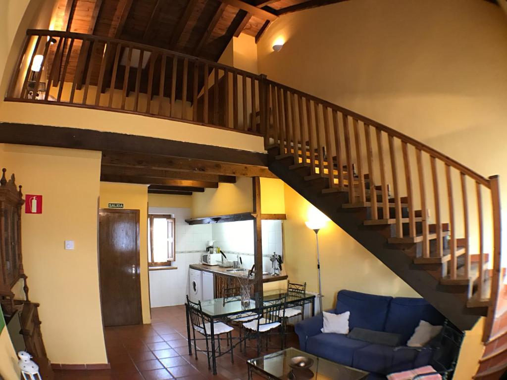 sala de estar con sofá azul y escalera en El Bulin de Horcajuelo, en Horcajuelo de la Sierra