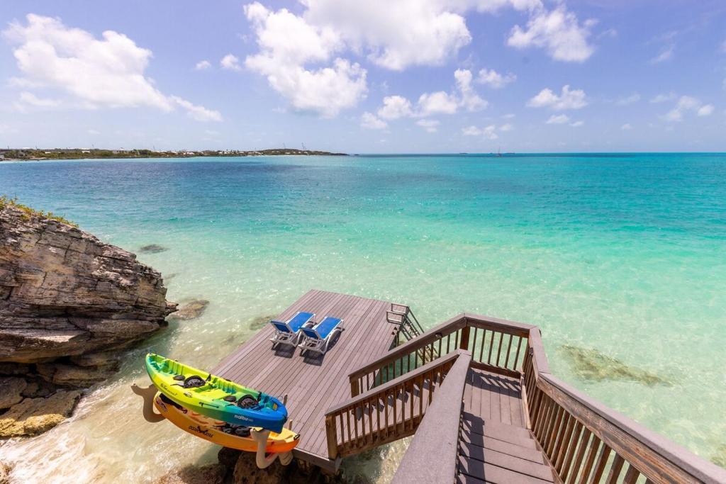 a dock with a boat and chairs on the beach at Villa La Percha in Providenciales