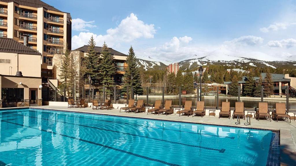 a swimming pool with chairs and mountains in the background at Mountain Valley Lodge Resort Studio Villa in Breckenridge