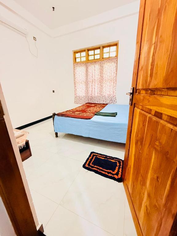 a room with a bed and a wooden door at Dew homestay in Wellawaya