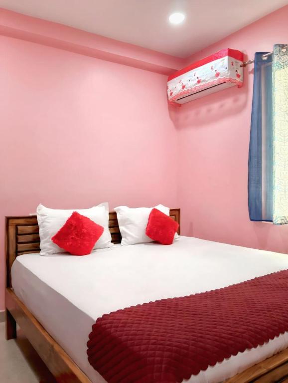 a bedroom with a bed with red and white pillows at BHS Deluxe Rooms in Puri