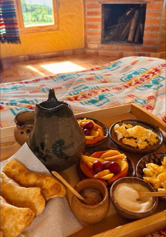 a tray filled with different types of food on a bed at Refugio del venado Cuicocha in Cotacachi