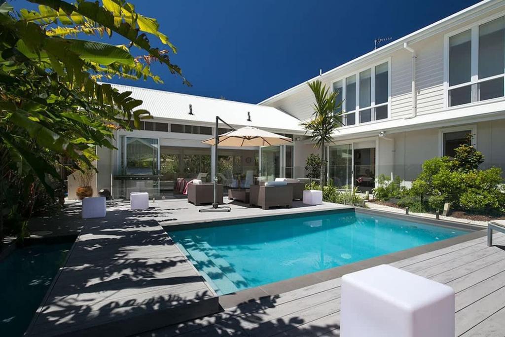 a swimming pool in front of a house at White Sands Beach House in Marcoola