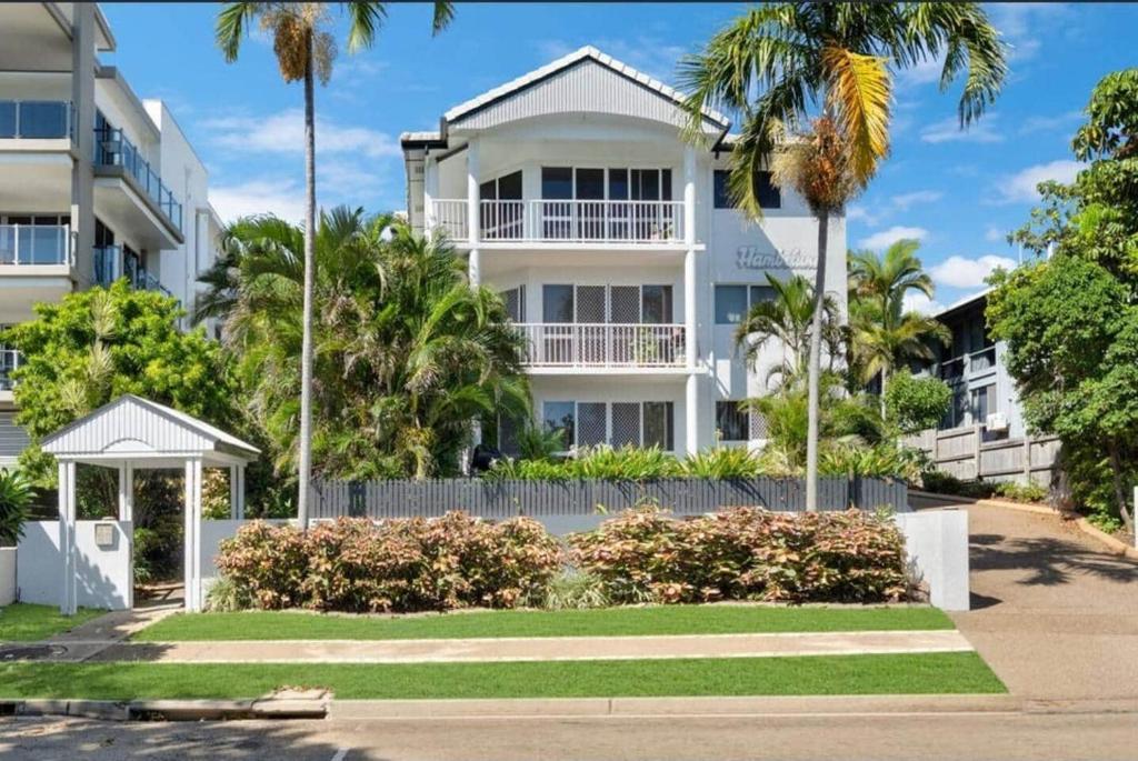 a white building with palm trees in front of it at Apartment on The Strand - 2 Bed 2 Bath in North Ward